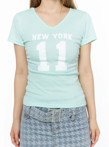 V-Neck Graphic Tee CL501 Mint close-up front shot on model showing V-neckline, white NEW YORK 11 graphic print, and ribbed stretch fabric texture