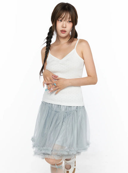 V-Neck Pointelle Cami Top CL514 White three-quarter front view on model with hands overlapping at waist showing pointelle texture with layered blue tulle skirt