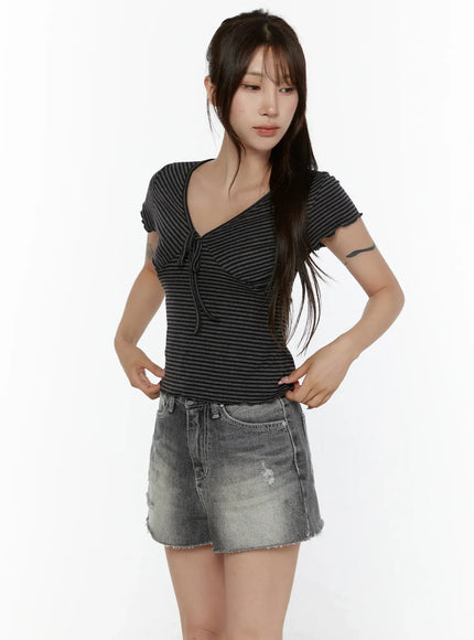 V-Neck Ribbon Striped Short Sleeve Tee CL507 Black front model three-quarter shot size S/M hands on waist showing V-neck ribbon tie and lettuce hem detail