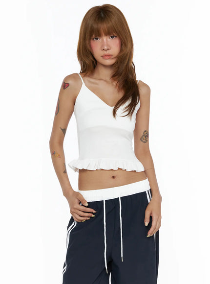V-Neck Ruffle Cami Top CL503 White front shot on model with hand on hip, fitted ribbed crop top with V-neck and pleated ruffle hem