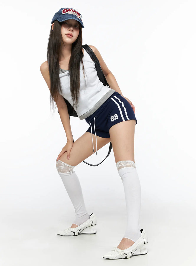 LEWKIN Varsity Athletic Shorts CL514 Dark blue full-body shot on model leaning forward wearing cap and lace knee-high socks sporty street styling