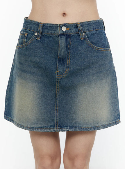 Vintage A-Line Denim Mini Skirt IL506 Blue front close-up detail shot on model showing silver button, front coin pocket, and twin side pockets with gold topstitching