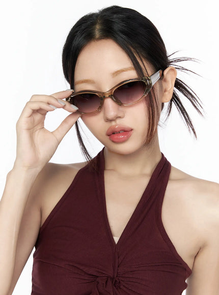 Vintage Cat Eye Fashion Sunglasses CL527 Beige One Size close-up model holding frame down posing with hand touching lens rim showing detailed frame construction