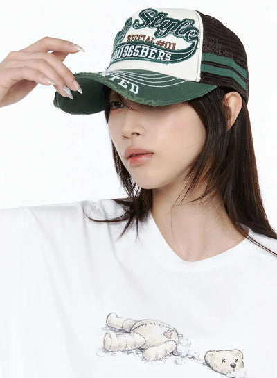 LEWKIN Vintage Graphic Cap IL506 Green close-up model shot, hand adjusting distressed brim, embroidered Only Style NUM1965BERS patch, mesh back