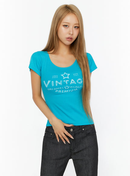 Vintage Graphic U-Neck Tee IL524 Turquoise front close-up on model wearing scoop neck tee with star VINTAGE graphic print paired with dark jeans