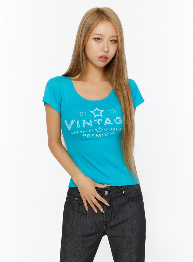 Vintage Graphic U-Neck Tee IL524 Turquoise front close-up on model wearing scoop neck tee with star VINTAGE graphic print paired with dark jeans