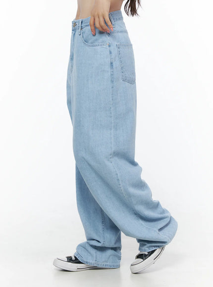 Viori Casual Wide-Leg Jeans IU525 Light blue side shot on model hand gripping waistband, showing exaggerated wide-leg silhouette and pooling hem over Converse sneakers