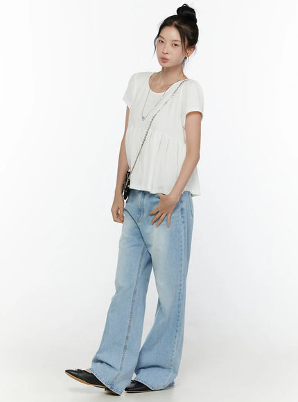 Wade Light Washed Wide Leg Jeans CL520 Light blue three-quarter front shot on model styled with white peplum top chain bag hand on hip showing wide leg fit