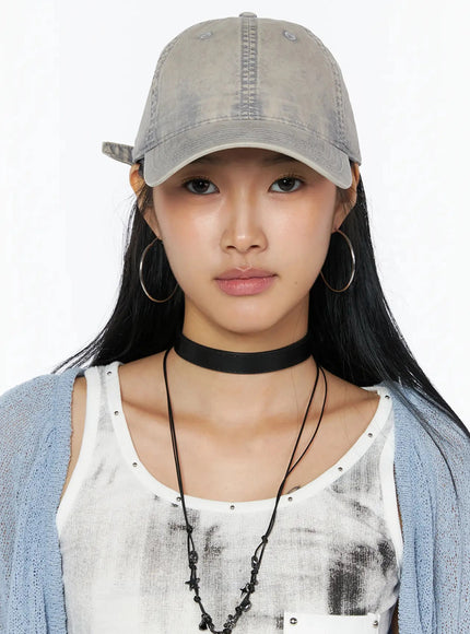 Washed Denim Cap IL509 Gray front portrait on model direct gaze washed faded cotton cap styled with blue cardigan choker necklace