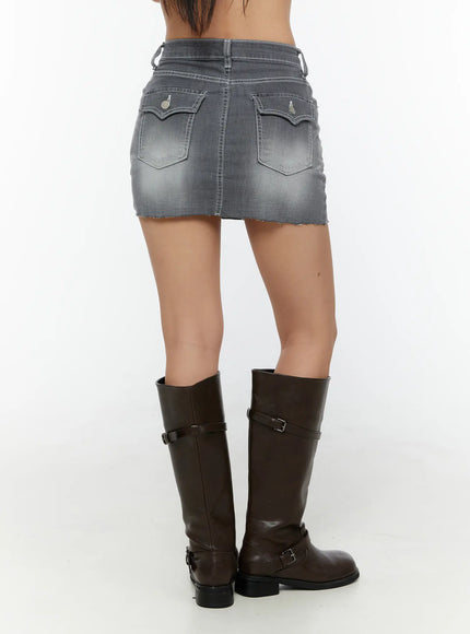 Washed Mid-Rise Denim Mini Skirt CU529 Gray back view on model showing dual flap back pockets with metal buttons, washed denim, raw hem, paired with brown riding boots
