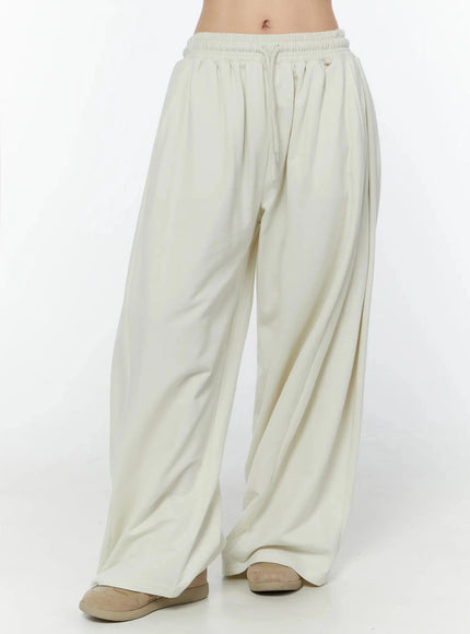 Wide Leg Sweatpants IU524 Light beige front view on model, angled waist-to-hem shot highlighting pleated wide-leg drape and drawstring elastic waistband