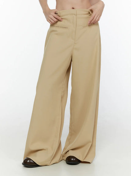 Wide Leg Tailored Pants CL520 Beige angled front close-up on model hands on waist highlighting belt loops slash pocket and tailored wide leg drape
