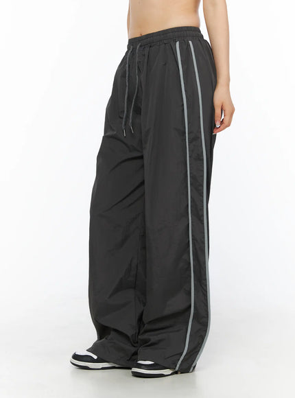 LEWKIN Wide Leg Track Pants CL501 Dark gray side view on model wearing sneakers, wide-leg silhouette with gray side stripe, nylon fabric