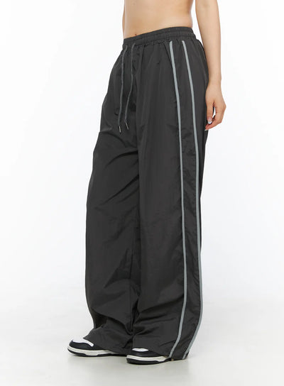 LEWKIN Wide Leg Track Pants CL501 Dark gray side view on model wearing sneakers, wide-leg silhouette with gray side stripe, nylon fabric