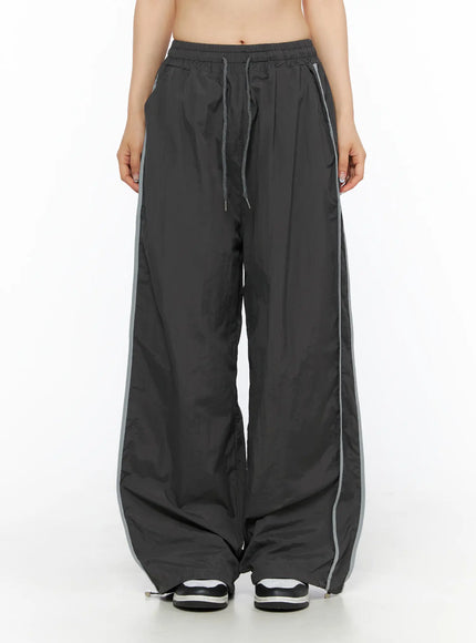 Wide Leg Track Pants CL501 Dark gray front view on model, wide-leg silhouette with drawstring waist, dual reflective gray side stripes, nylon
