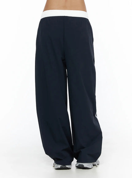 Wide Leg Track Pants CL503 Dark blue back shot on model, white ribbed elastic waistband, wide-leg baggy fit pooling at hem, silver sneakers