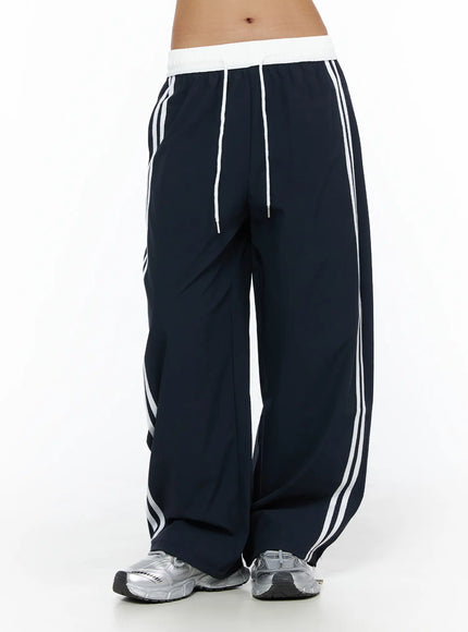Wide Leg Track Pants CL503 Dark blue front three-quarter shot on model, white elastic waistband with drawstring, double white side stripes, wide-leg baggy fit