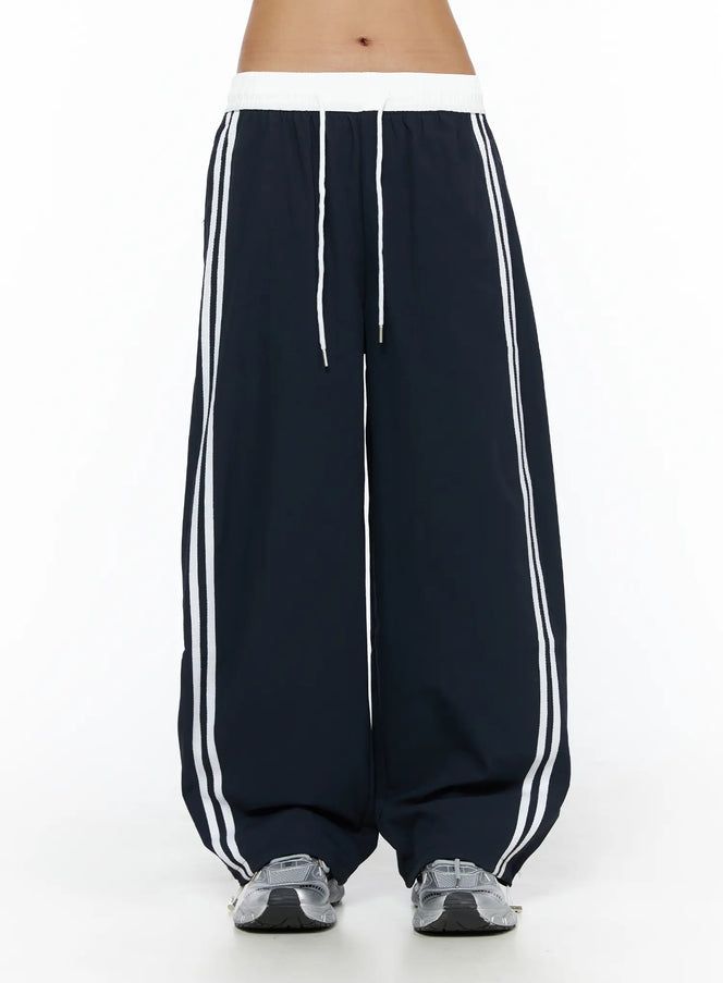 Wide Leg Track Pants CL503 Dark blue front close-up on model, white ribbed elastic waistband with drawstring, double white side stripes, wide-leg fit