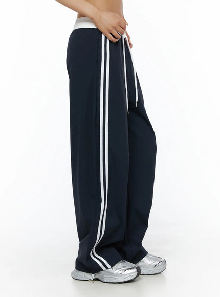 Wide Leg Track Pants CL503 Dark blue side close-up on model, double white side stripes visible, white elastic waistband, drawstring detail, wide-leg silhouette