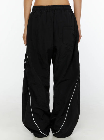 Wide-Leg Track Pants CL515 Black back shot on model showing elastic waistband rear pocket and white piping detail on wide nylon legs
