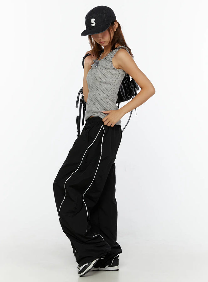 LEWKIN Wide-Leg Track Pants CL515 Black M/L front shot on model styled with gray tank top and black cap, wide nylon pants with white piping