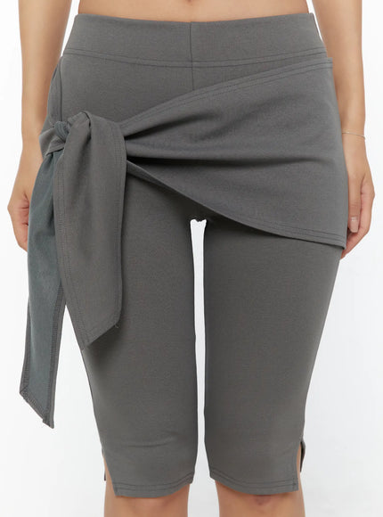 Wrap Capri Pants CU526 Dark gray close-up front model showing wrap skirt tie knot detail stitching and layered skirt overlay over capri legging waistband