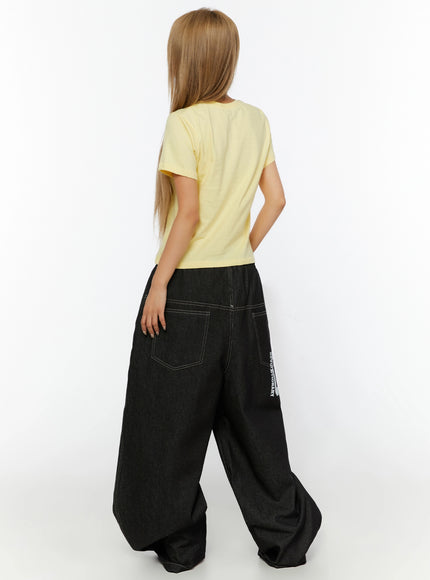 Youth Graphic Short Sleeve Tee IL524 Yellow back view on model showing plain yellow cropped back, paired with dark wide-leg denim with contrast stitching