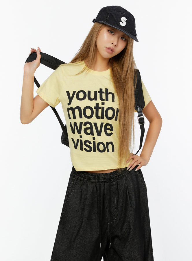 LEWKIN Youth Graphic Short Sleeve Tee IL524 Yellow front view on model wearing black cap and backpack, styled with wide-leg dark pants, S/M