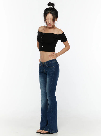 Zainab Low-Rise Flared Bootcut Jeans CU529 Dark blue full-body front shot on model in black off-shoulder crop top, looking down with hand on waist