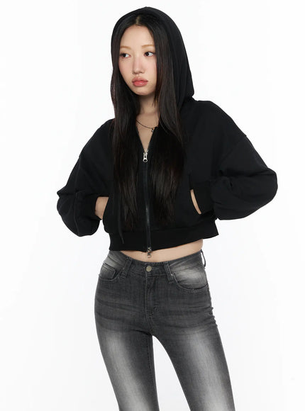 Zip-Up Crop Hoodie CL527 Black half-body front shot on model wearing hood up hands on hips zip partially open over gray jeans