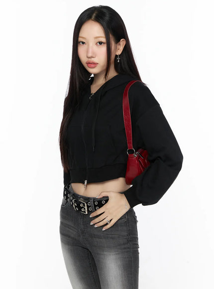 LEWKIN Zip-Up Crop Hoodie CL527 Black 3/4 side shot on model styled with grommet belt and red shoulder bag over gray jeans