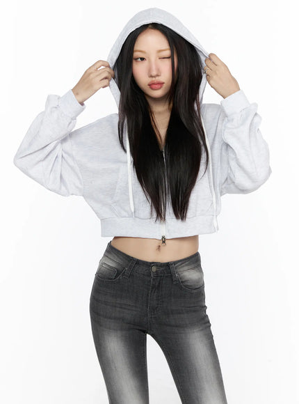 Zip-Up Crop Hoodie CL527 Light Gray front shot on model holding hood up with both hands paired with faded gray skinny jeans