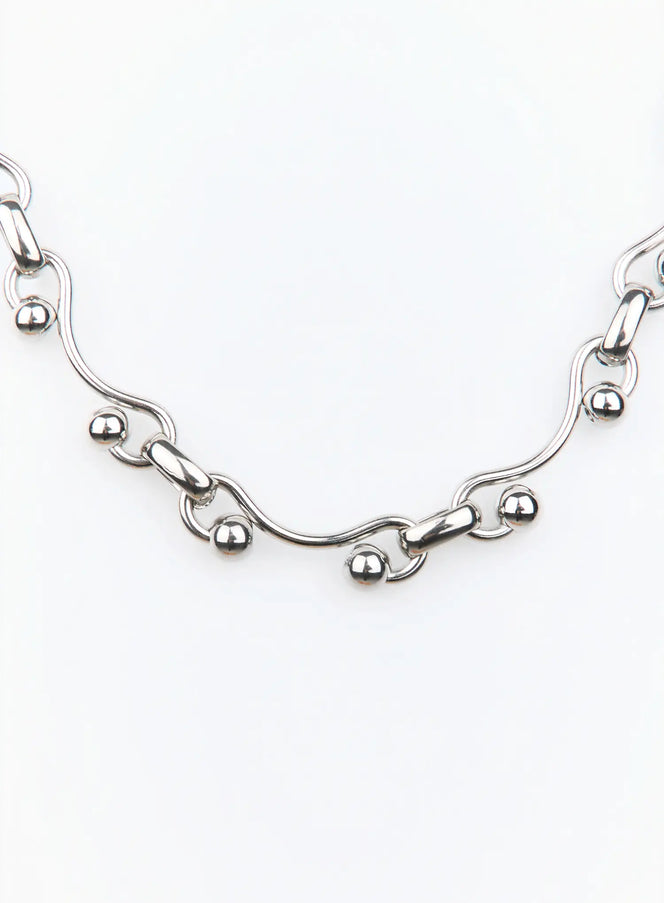 Ravel Necklace IU503 in silver, flat detail close-up, wavy elongated links with polished ball charms, high-shine silver-tone metal, no clasp visible.