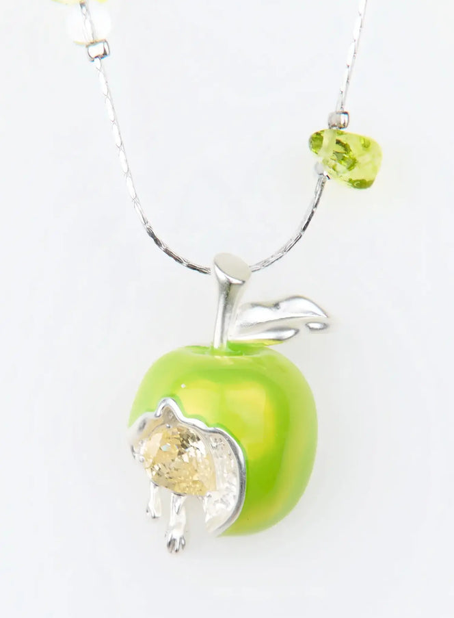 Corbusier Necklace IU503 close-up flat shot, green apple pendant with silver leaf, crystal-filled bite cutout, and green faceted bead on silver chain.