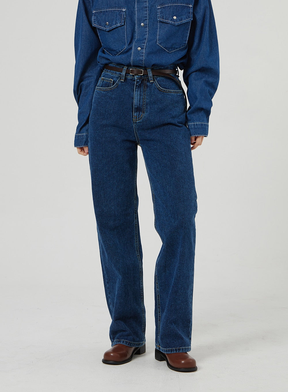 Basic Indigo Jeans OF310 in indigo, waist-to-hem front close-up on model, high-rise fit with five-pocket construction and contrast stitching, belted with brown leather, worn with denim shirt.