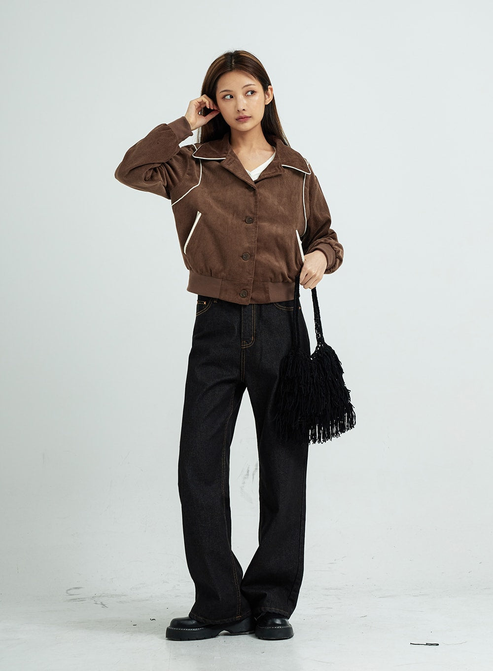 LEWKIN Pepe Wide Pants CS15 in black, full-length front view on model, wide-leg cotton denim with contrast stitching, styled with brown cropped jacket and black fringe bag.