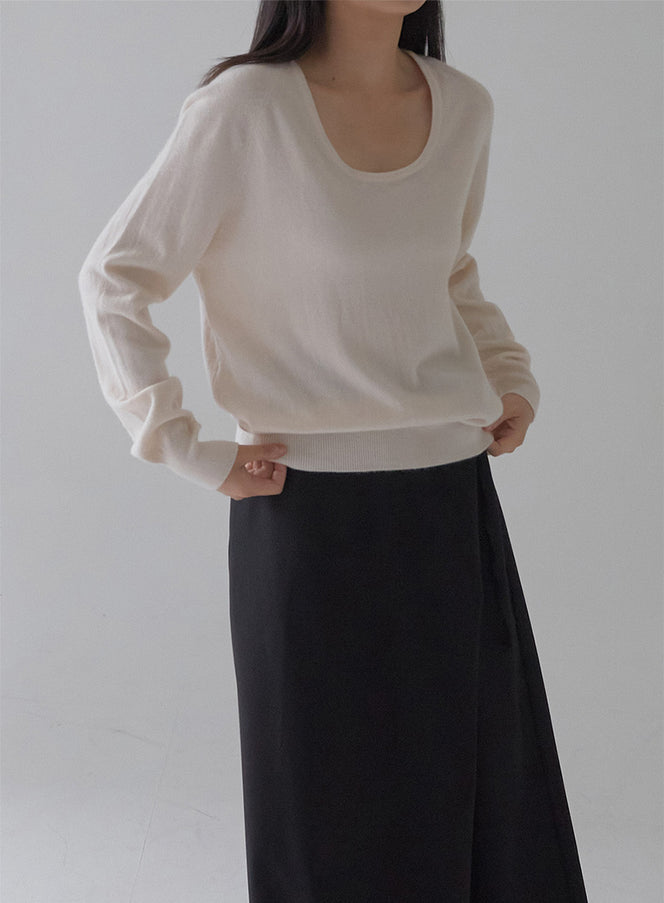 All Day Round Round Neck Knit in ivory, front closer crop on model, U-neckline and relaxed long sleeve knit sweater with ribbed cuff, styled with black wrap skirt.
