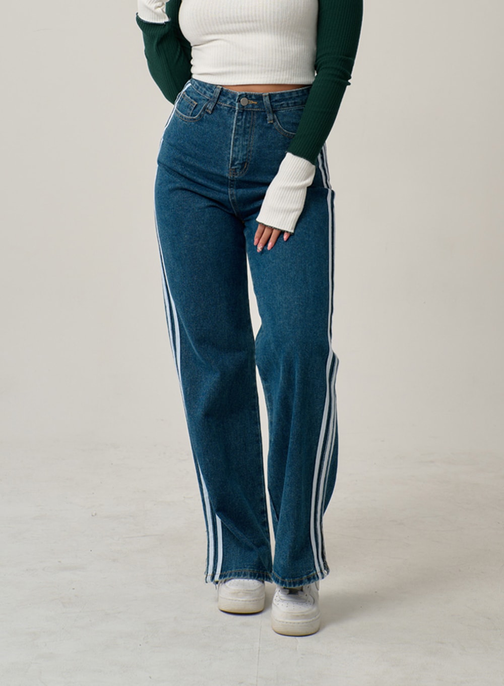 LEWKIN Side Stripes Straight Leg Jeans IN22 in mid blue, front view on model, wide-fit high-rise denim with three white side stripes, paired with ribbed crop top and white sneakers.