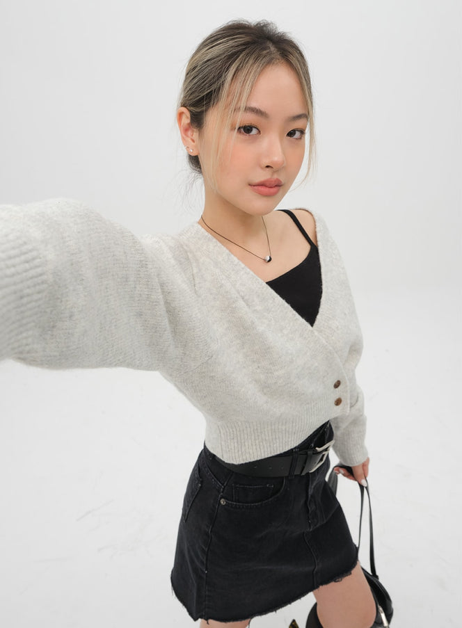 Cami C2001 in black, close-up selfie-angle on model, thin strap and square neckline visible under an oatmeal knit cardigan, layered street look.