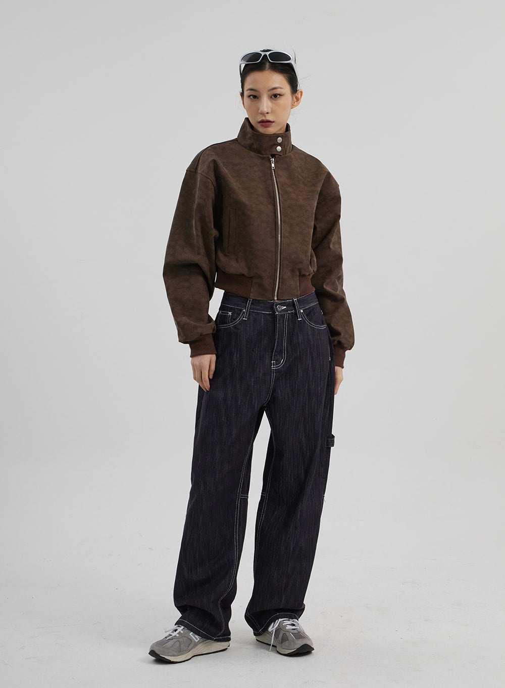 LEWKIN Mid-Rise Baggy Jeans CF307 in dark indigo, full-body front view on model, wide-fit cotton denim with white contrast stitching, paired with brown cropped jacket and sneakers.