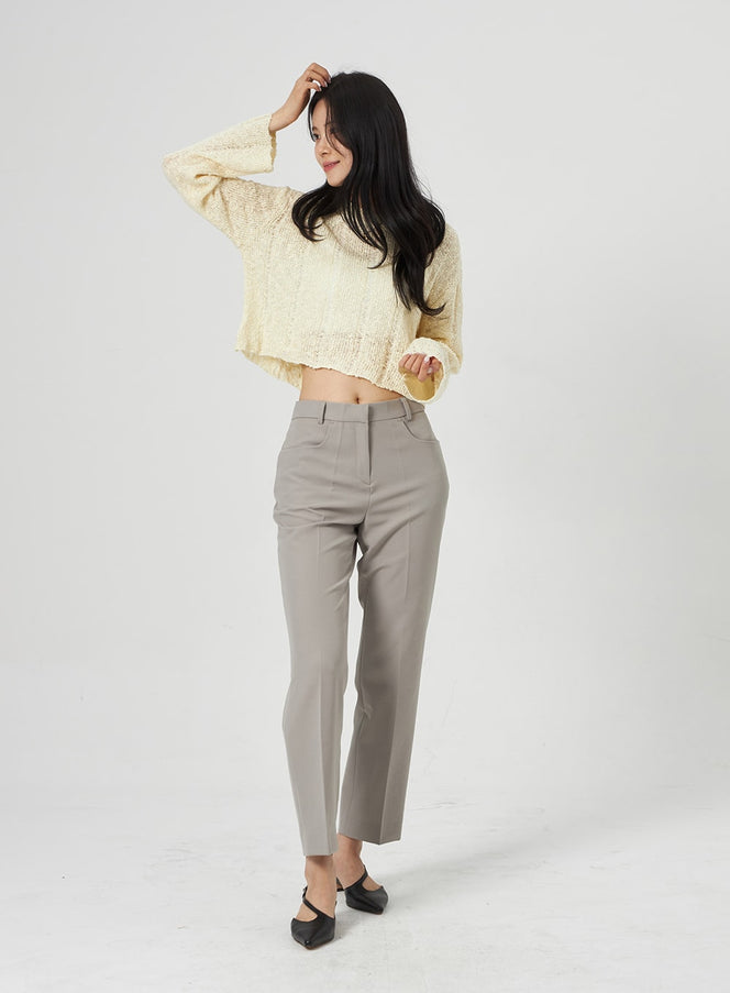 LEWKIN Ankle Tailored Pants OA314 in grey, three-quarter angle on model, straight-fit polyester trousers with front crease, hands-in-hair pose, paired with cream crop knit and black mules.