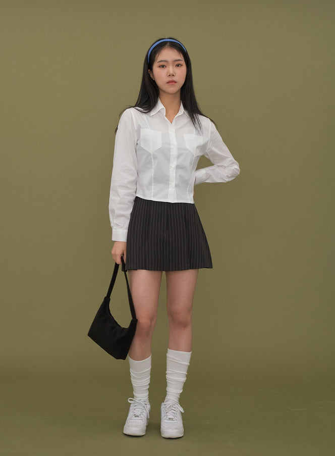 LEWKIN Cropped Shirt with Pockets C2601 in white, full-body front on model, slim-fit cotton long sleeve with dual chest pockets, paired with pinstripe mini skirt and white sneakers.