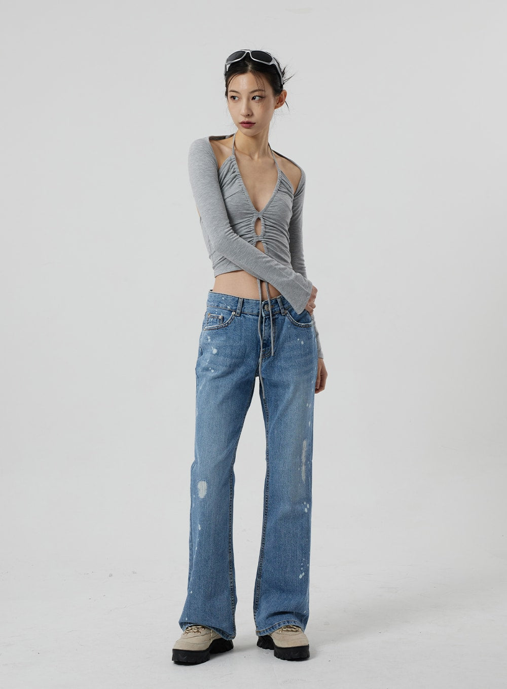 LEWKIN Low Rise Bootcut Jeans CF309 in blue denim, full-length front view on model, slim fit with paint-splatter distressing and bootcut hem, styled with grey ruched halter crop top and chunky sneakers.