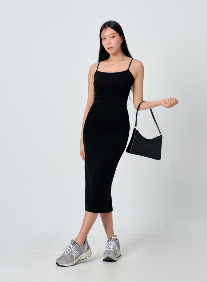 LEWKIN Thin Strap Maxi Dress IJ330 in black, front three-quarter view on model, slim-fit sleeveless midi dress with thin spaghetti straps, paired with black shoulder bag and grey sneakers.