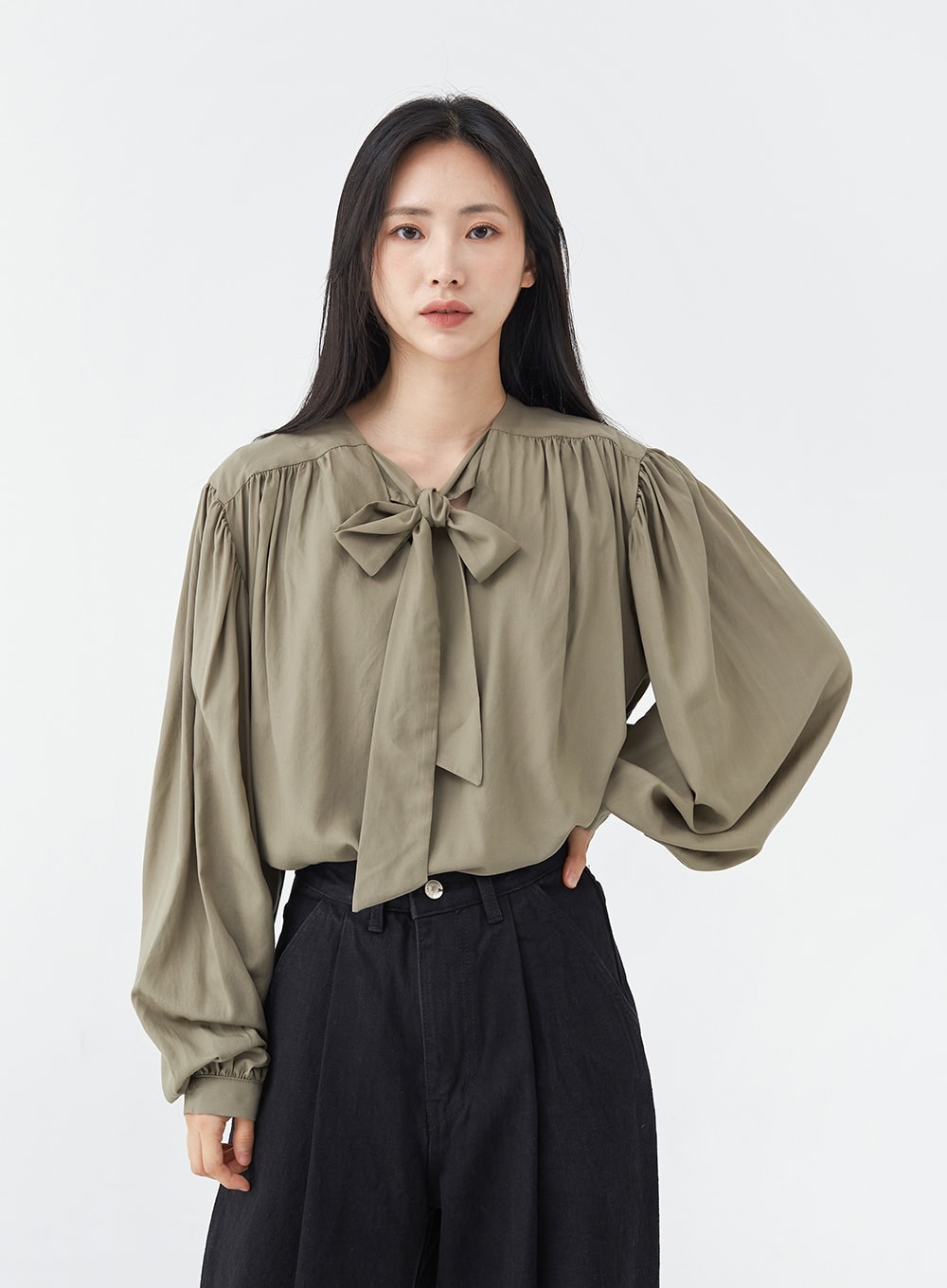 Pintuck Black Jeans OG18 in black, upper-body and waistband close-up on model, wide-fit cotton showing high-rise waist and pintuck folds, paired with olive bow blouse.