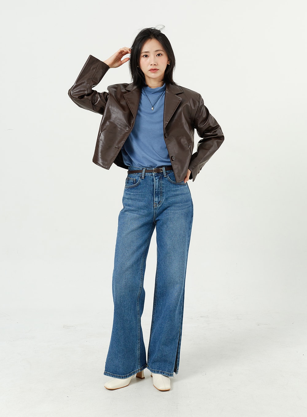LEWKIN Side Slit Jeans OM308 in mid blue, full-length front shot on model, wide-leg cotton denim with hem side slits, styled with brown leather jacket and white boots.