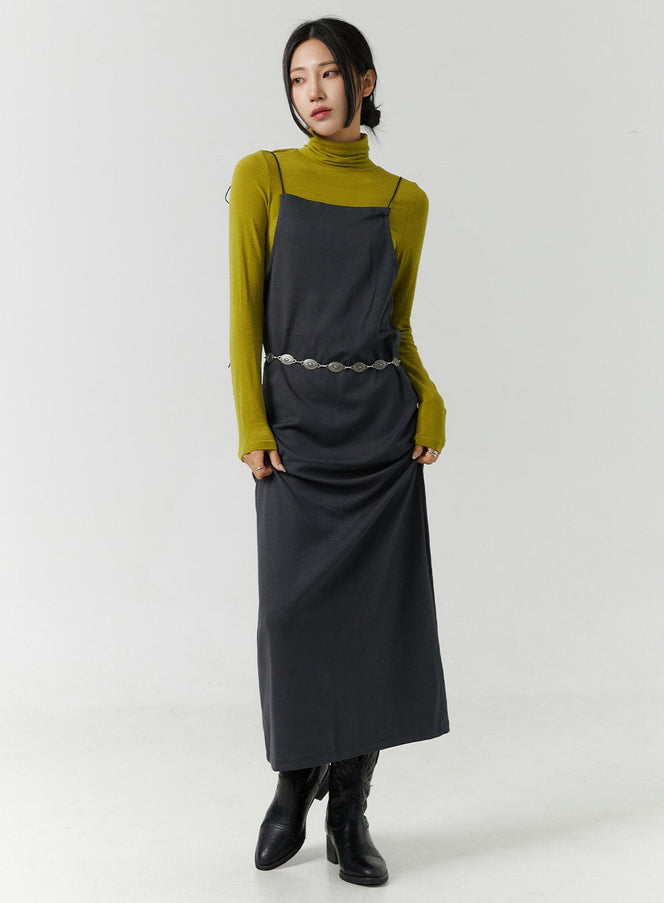 LEWKIN Open Back Strap Sleeveless Maxi Dress CN328 in dark gray, full-length front on model, layered over mustard turtleneck with silver chain belt and black boots.