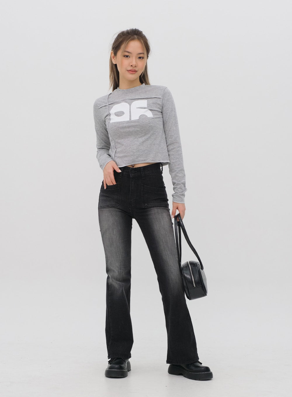 LEWKIN Bootcut Jeans M4 in black gradation wash, full-length front view on model, high-waist patch pockets, bootcut flare leg, paired with grey crop top and black bag.