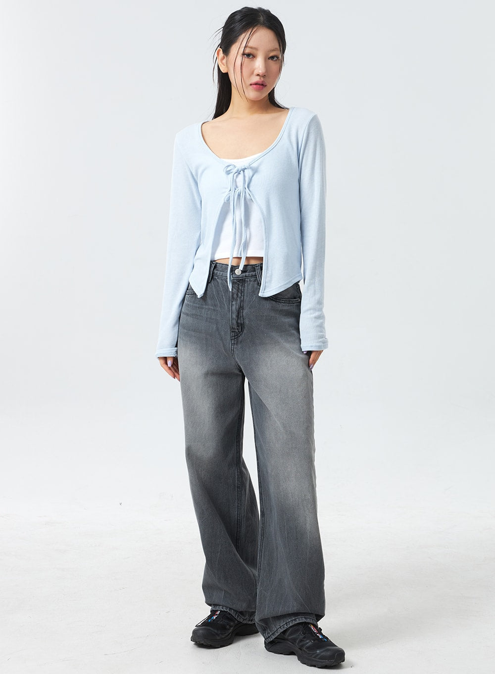 LEWKIN Low Rise Mid-Wash Jeans CM327 in grey, full-length front shot on model, wide-fit cotton denim with faded wash, low waist, paired with light blue tie-front crop cardigan and chunky sneakers.