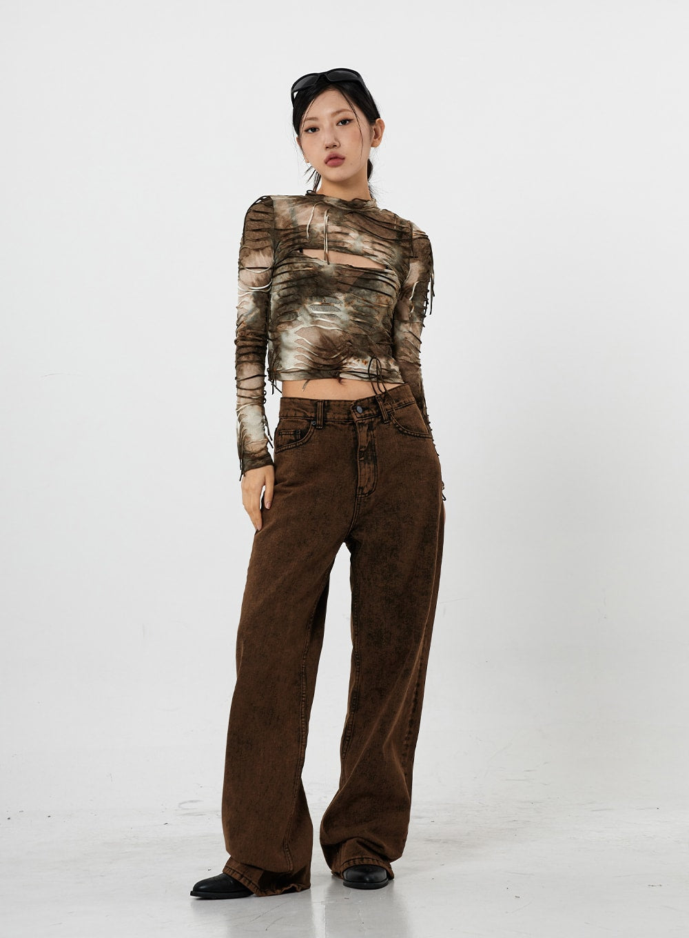 LEWKIN Washing Wide Jeans Unisex CS21 in brown, full-length front view on model, washed gradation cotton denim, wide-leg silhouette pooling at hem, paired with tie-dye mesh crop top and black loafers.